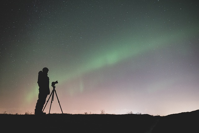 Silhouette of a guy with his camera, looking up at the view of the aurora borealis.
