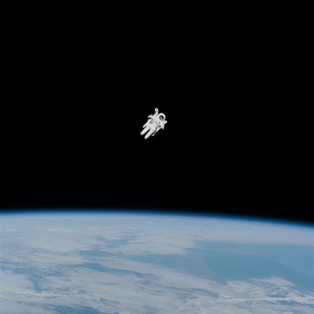An astronaut in space, with the earth underneath.