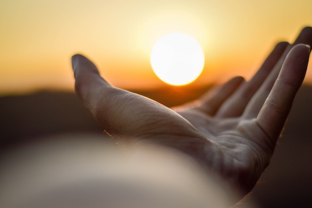 An outstretched, open palm, pointing towards the sun