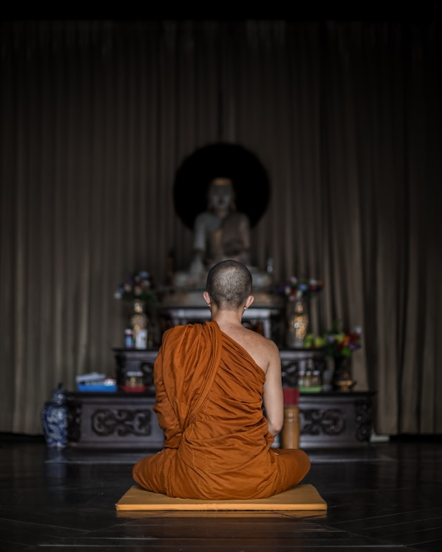 A Buddhist monk meditating in front of an altar