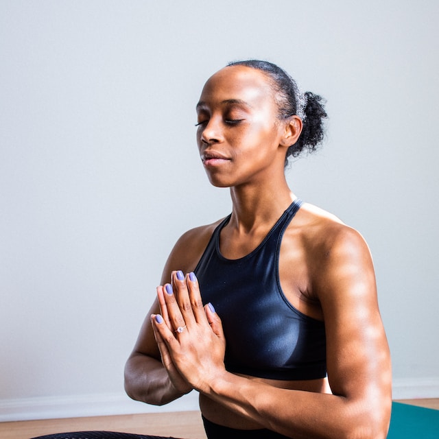 A woman with her hands clasped and eyes closed while meditating