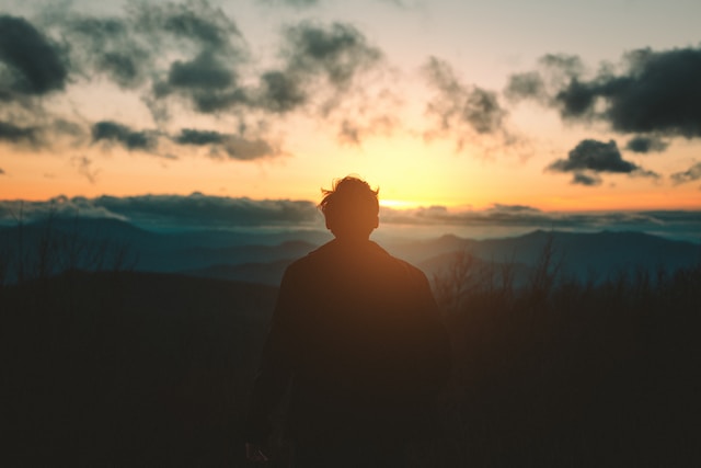 A man meditates while looking at the sunrise