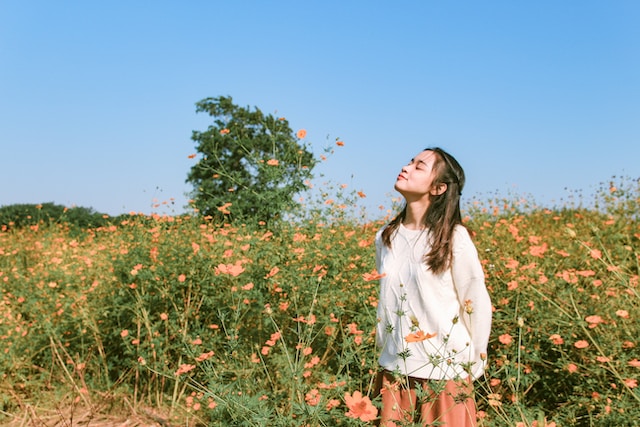 Woman with eyes closed, face turned upwards in a field of flowers
