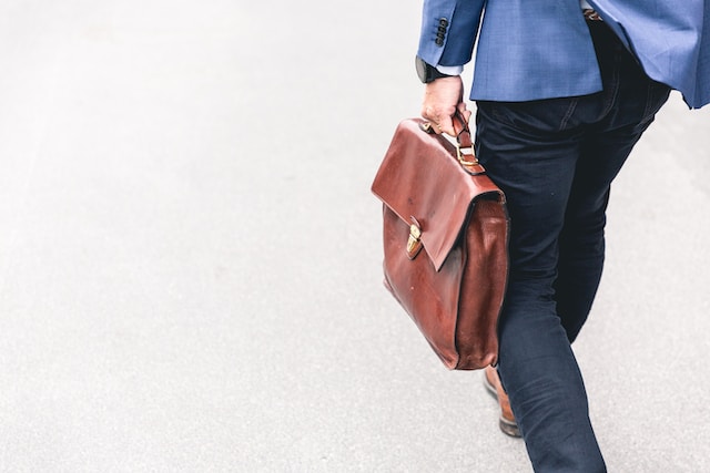 Person carrying a brown leather messenger bag