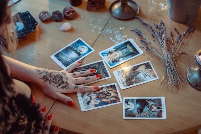 Woman with red nails touching tarot cards on a table