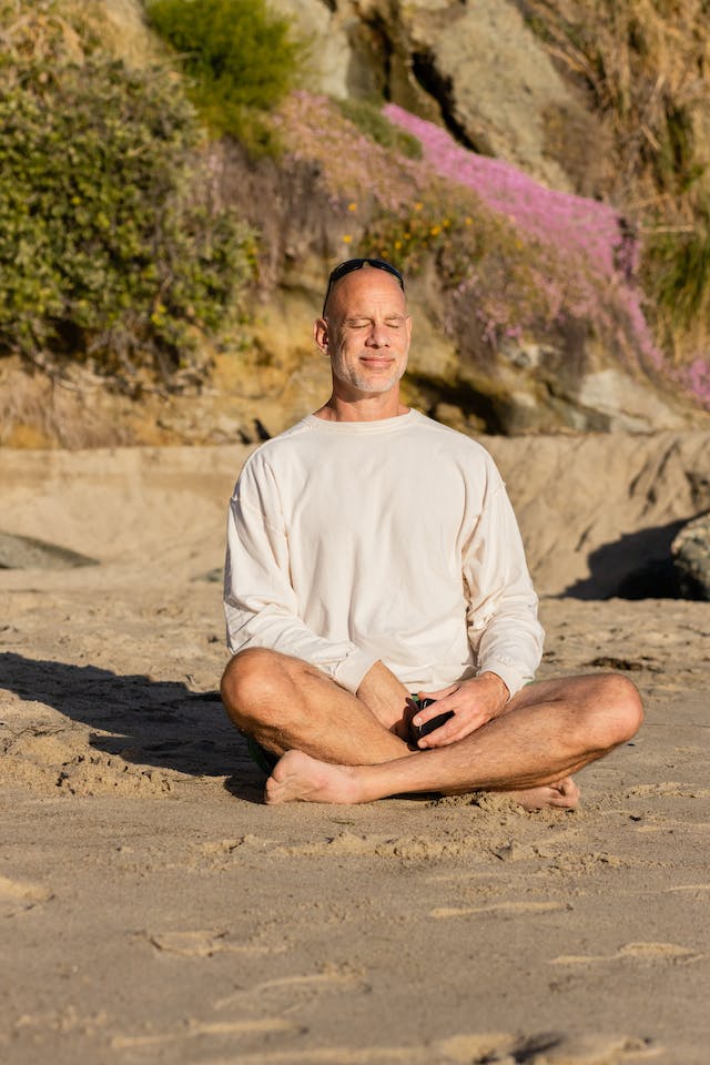 Mature man meditating on a beach