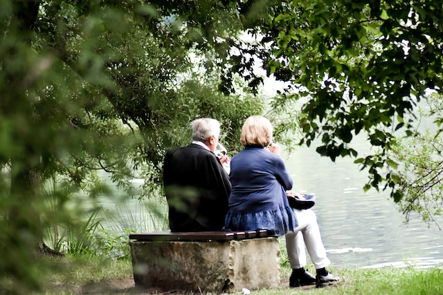 Older couple drinking wine and enjoying the lake view before them