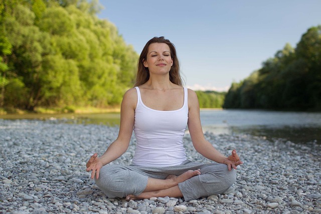 Woman sitting cross legged on a rocky surface while meditating